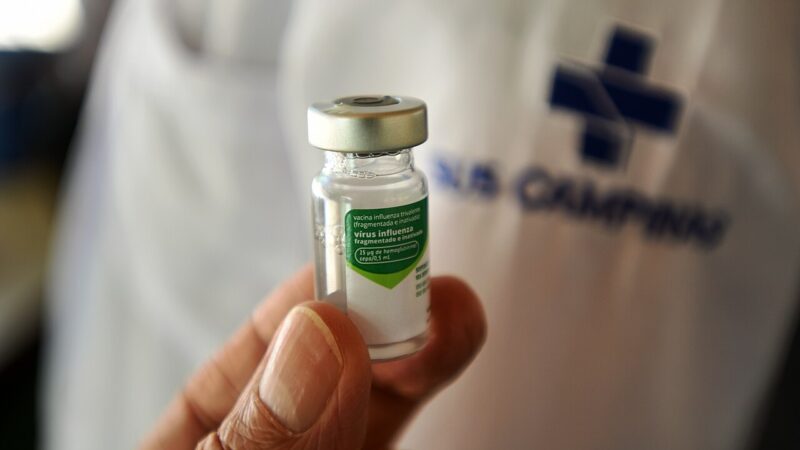 A health worker holding a vial of flu vaccine